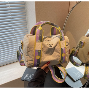 Vista dettagliata della borsa a cilindro in nylon beige con manici colorati