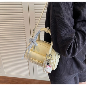 Detail of a creamy yellow bowling bag featuring lace trim and a blue checkered ribbon bow