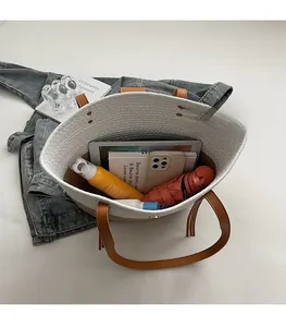 Vista dall'alto della borsa tote intrecciata capiente che mostra l'interno con accessori