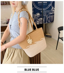 Detail of two-tone woven straw tote bag with wave texture and floral charm