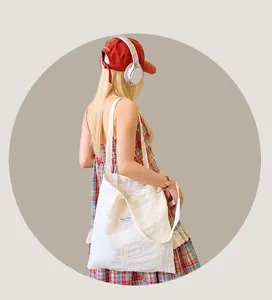 Detail of white canvas tote bag featuring delicate lace embroidery and woven side label