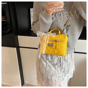 Détail du sac en cuir matelassé jaune avec nœud en dentelle et chaîne en perles de style