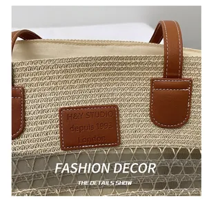 Dettaglio borsa tote in paglia con manico in pelle marrone e toppa con logo in rilievo