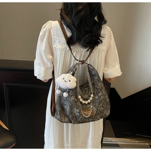 Detail of grey floral tote bag with pearl chain and cloud charm on a shoulder