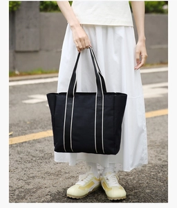 Detail of black and white canvas tote bag with reinforced X-shaped handle stitching