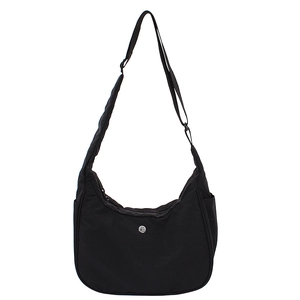 Sac hobo en toile noire avec bandoulière réglable et logo argenté sur fond blanc épuré