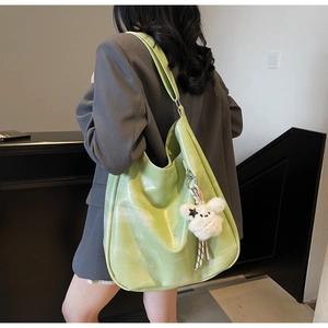 Détail du sac cabas vert clair en similicuir brillant avec pendentif en peluche blanc