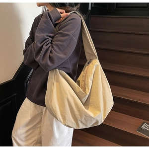Détail du sac hobo en nylon crème avec large bandoulière et forme en croissant