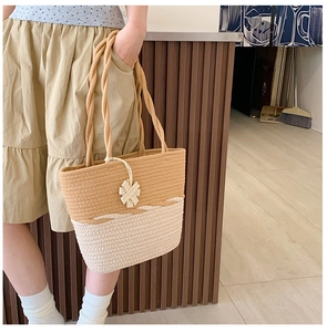 Detail of two-tone woven tote bag with contrast colors and decorative flower charm