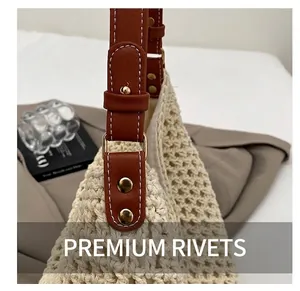 Detailed close-up of premium gold rivets on brown leather strap of woven straw bag