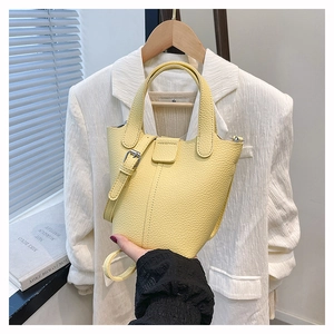 Detail showing high-quality lychee texture and silver buckle on yellow bucket bag