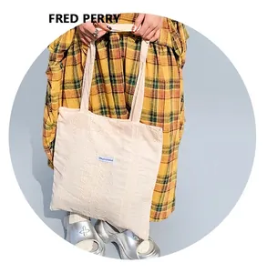 Detail of off-white tote bag with geometric lace texture and Magioppooket logo tag