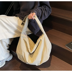 Vue détaillée du sac hobo en nylon crème montrant la fermeture éclair et la texture