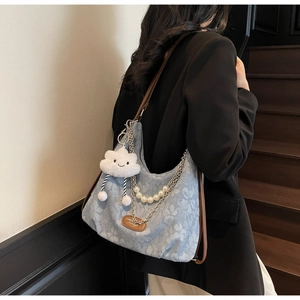 Sac fourre-tout à fleurs avec bandoulière cuir et chaîne de perles porté par un modèle