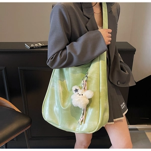 Détail du cabas en cuir vert clair avec texture nuage et breloque ours en peluche