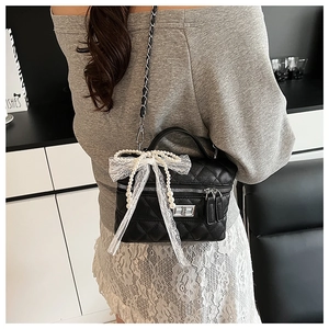Détail du sac bandoulière matelassé avec chaîne en perles et nœud en dentelle