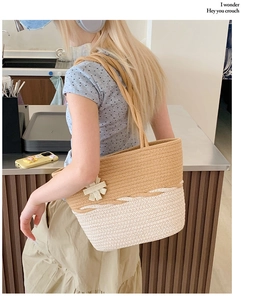Detail of hand-woven straw tote bag featuring two-tone design and floral charm