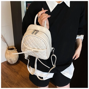 Détail du mini sac à dos matelassé crème avec nœud en cuir et finition brillante