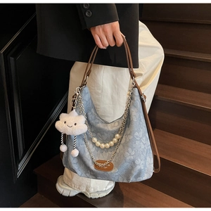 Détail du sac hobo en denim floral avec chaîne de perles, sangle et pendentif nuage