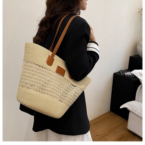 Borsa tote in paglia con manici in pelle indossata per mostrare capacità e stile