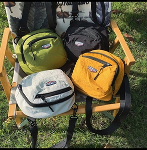 Quattro borse a tracolla in nylon nei colori verde nero giallo e bianco sporco all'aperto
