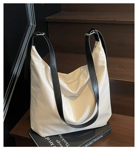 Detail of white nylon tote bag with black leather straps on a wooden staircase