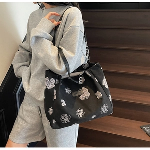 Detail of black canvas tote bag with white floral patterns and SAKURA DIARY patch