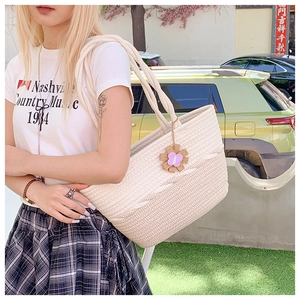 Detailed close-up of woven tote bag texture with sunflower charm and bicolor straw pattern
