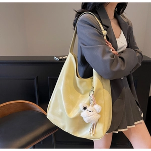 Détail d'un sac cabas en similicuir jaune vif avec un charm de chat en peluche blanche