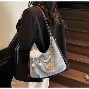Détail du sac cabas floral avec chaîne de perles et pendentif nuage blanc sur escalier