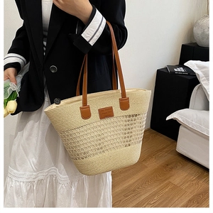 Dettaglio della borsa tote in paglia intrecciata a mano con design a rete e manici marroni