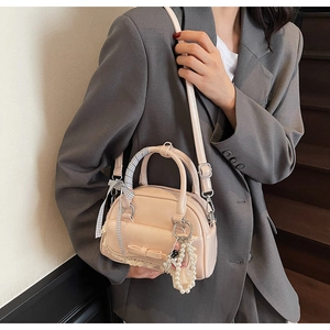 Détail du sac à main abricot avec charms en perles et dentelle porté par un mannequin