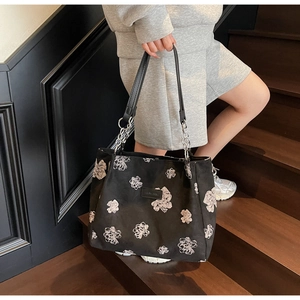 Detail of floral tote bag featuring leather chain straps and metallic brand logo plate