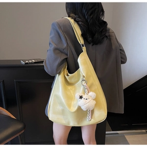 Gros plan du sac hobo jaune beurre avec breloque ours en peluche sur un mannequin