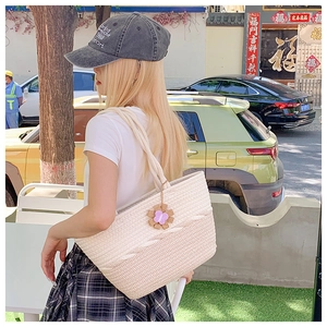 Outdoor shot of a woven straw tote bag with floral charm and casual baseball cap