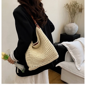 Detail of hand-woven off-white straw hobo bag with premium brown leather strap
