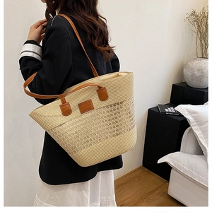 Dettaglio della borsa tote in paglia intrecciata con manici in pelle marrone e logo