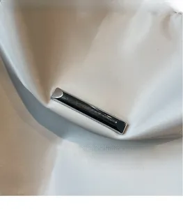 Close-up of modern silver hardware on smooth nylon fabric of a minimalist tote bag