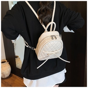 Vue détaillée du dos d'un mini sac à dos matelassé blanc crème sur un modèle avec nœud