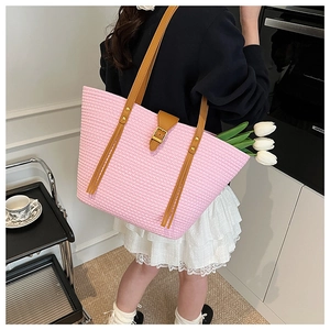 Dettaglio della borsa tote intrecciata rosa con manici in pelle marrone e fiori tulipani