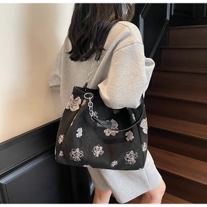 Detail of a large black printed tote bag with white floral patterns and silver metal chain