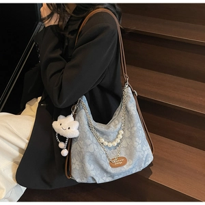 Détail d'un cabas floral bleu clair avec chaîne en perles et charme nuage