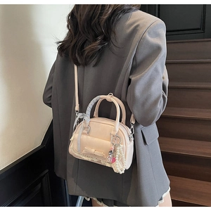 Pink bowling bag with bow and lace details worn by model on a dark grey blazer