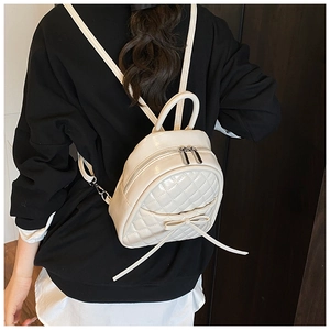 Détail du mini sac à dos matelassé crème avec nœud porté au dos par un mannequin