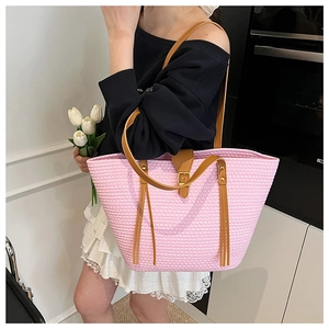 Dettaglio ravvicinato della borsa tote rosa intrecciata con nappe in pelle e tracolla