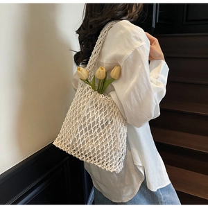 Detail of white handmade macrame bucket bag with hollow woven texture and shoulder strap
