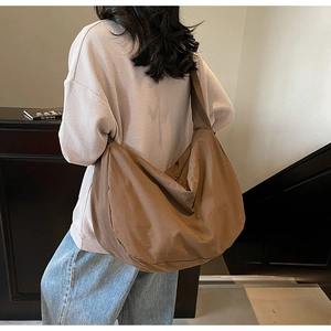 Détail d'un grand sac croissant en nylon marron porté en bandoulière pour un look décontracté