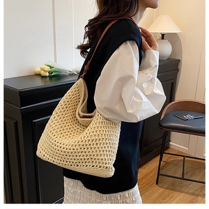Detail of hand-woven beige straw shoulder bag with dark brown leather strap for summer