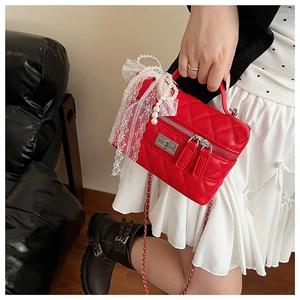 Détail du sac boîte rouge matelassé avec anse en perles et fermoir rotatif argenté