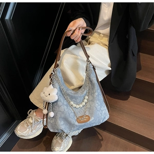 Détail du sac en jean floral avec breloques en perles, chaînes et pendentif nuage doux